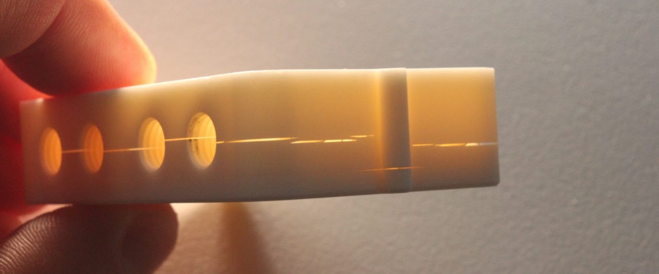 Durchleuchtetes Bauteil aus technischer Keramik mit einem durchgehenden Riss durch mehrere Bohrungen – Folge einer nicht keramikgerechten Konstruktion